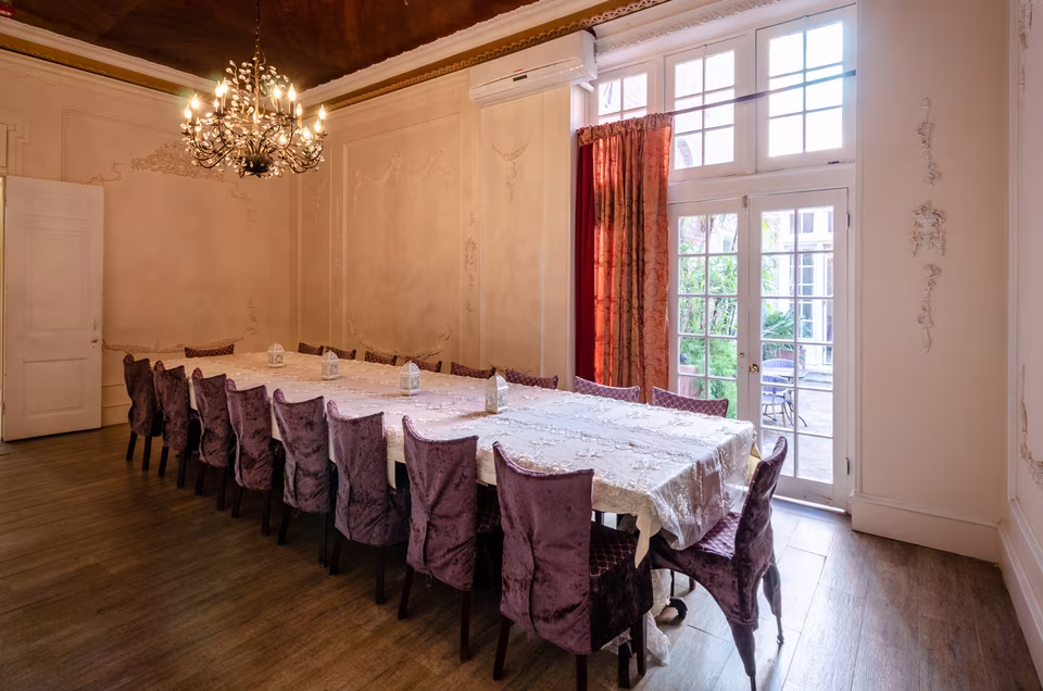 Reverse angle of the intimate private dining room with long banquet table, chandelier, and warm wood floor.