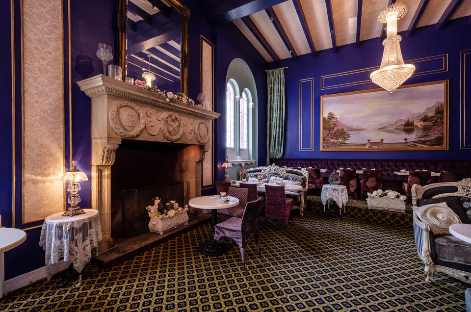Carved stone fireplace and crystal chandeliers anchoring the richly colored dining room.