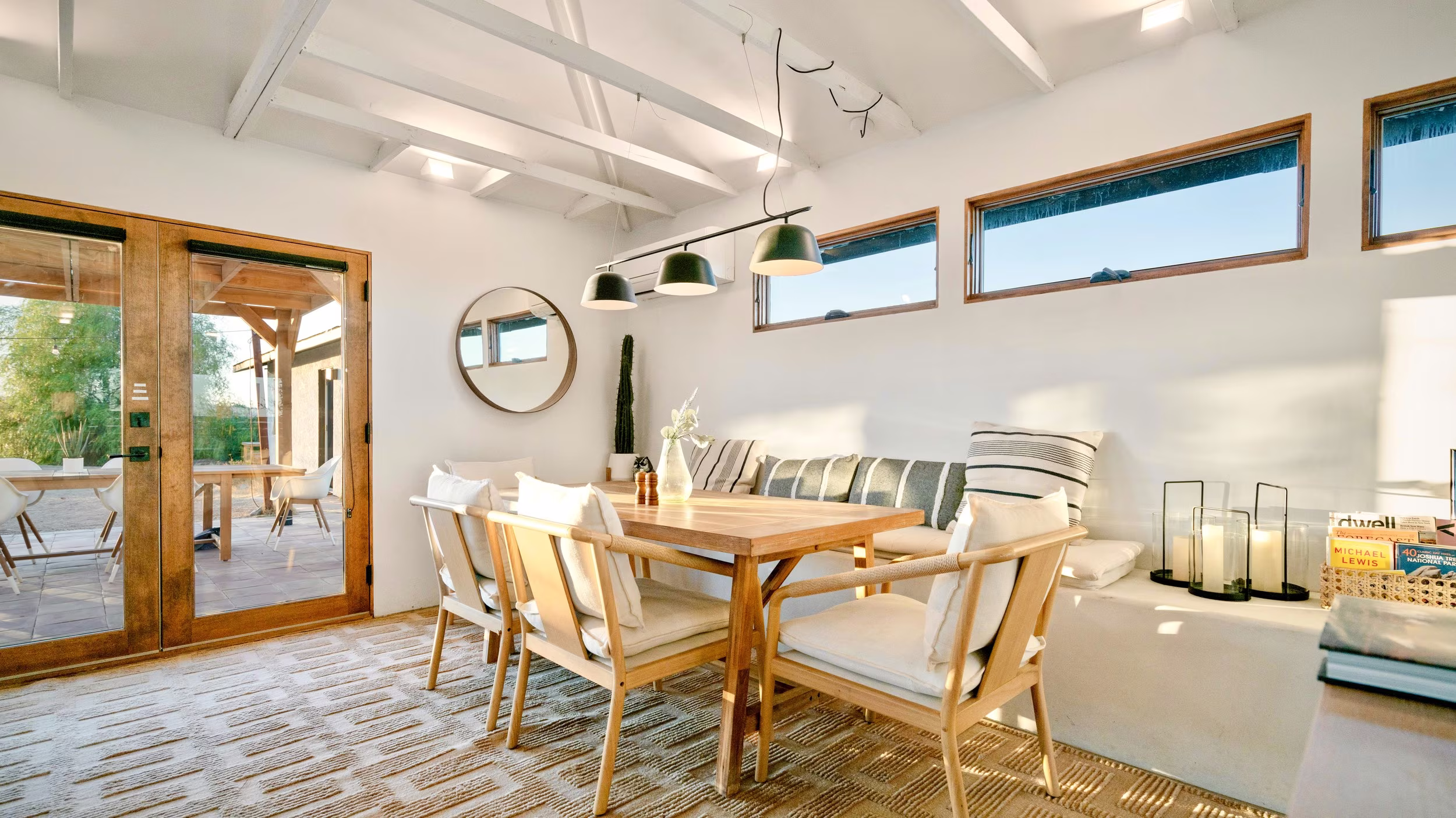 Wood dining table beside glass patio doors, narrow clerestory windows, and a built-in ledge.
