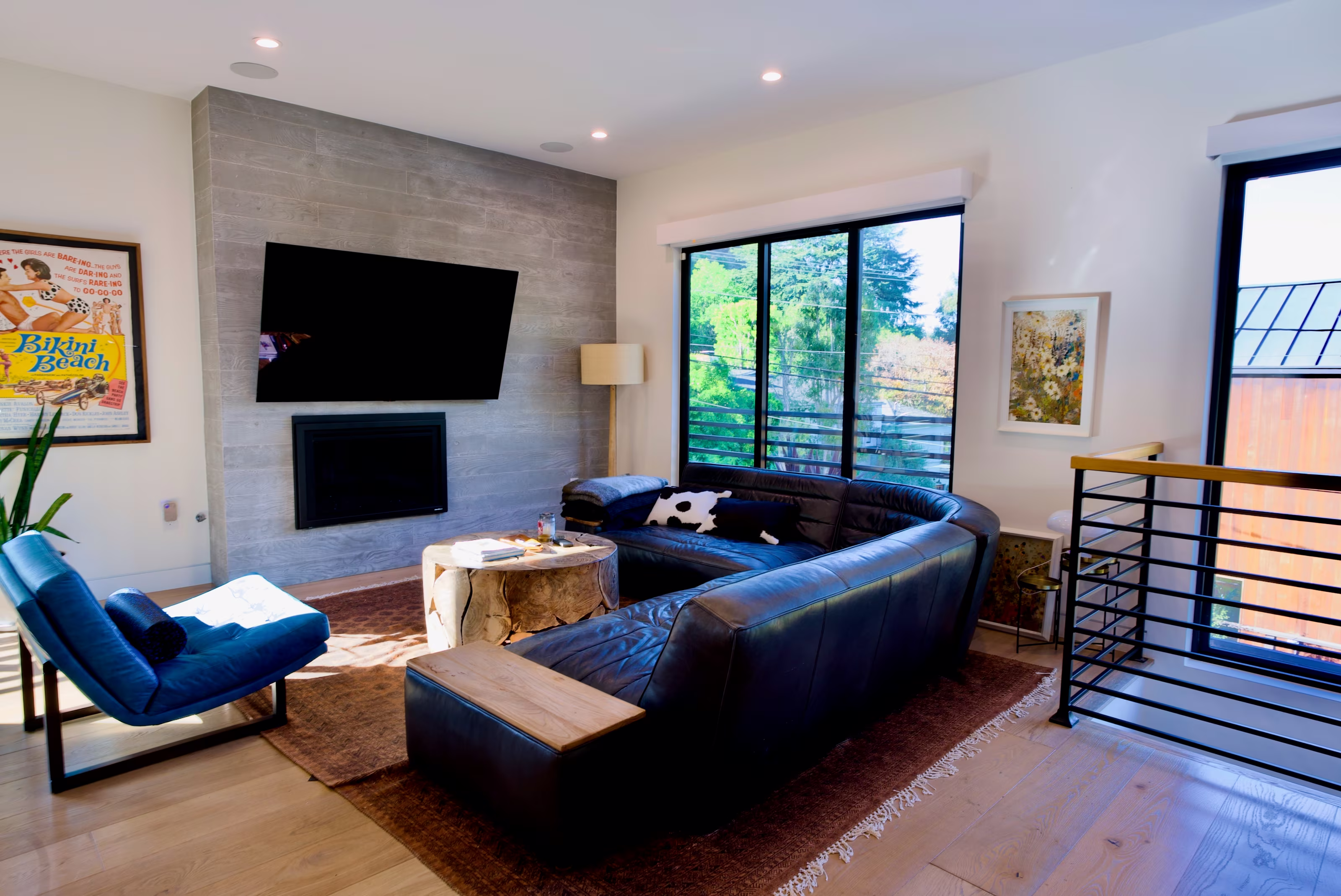 Living room arranged around a gray fireplace with black sectional and two blue chairs.