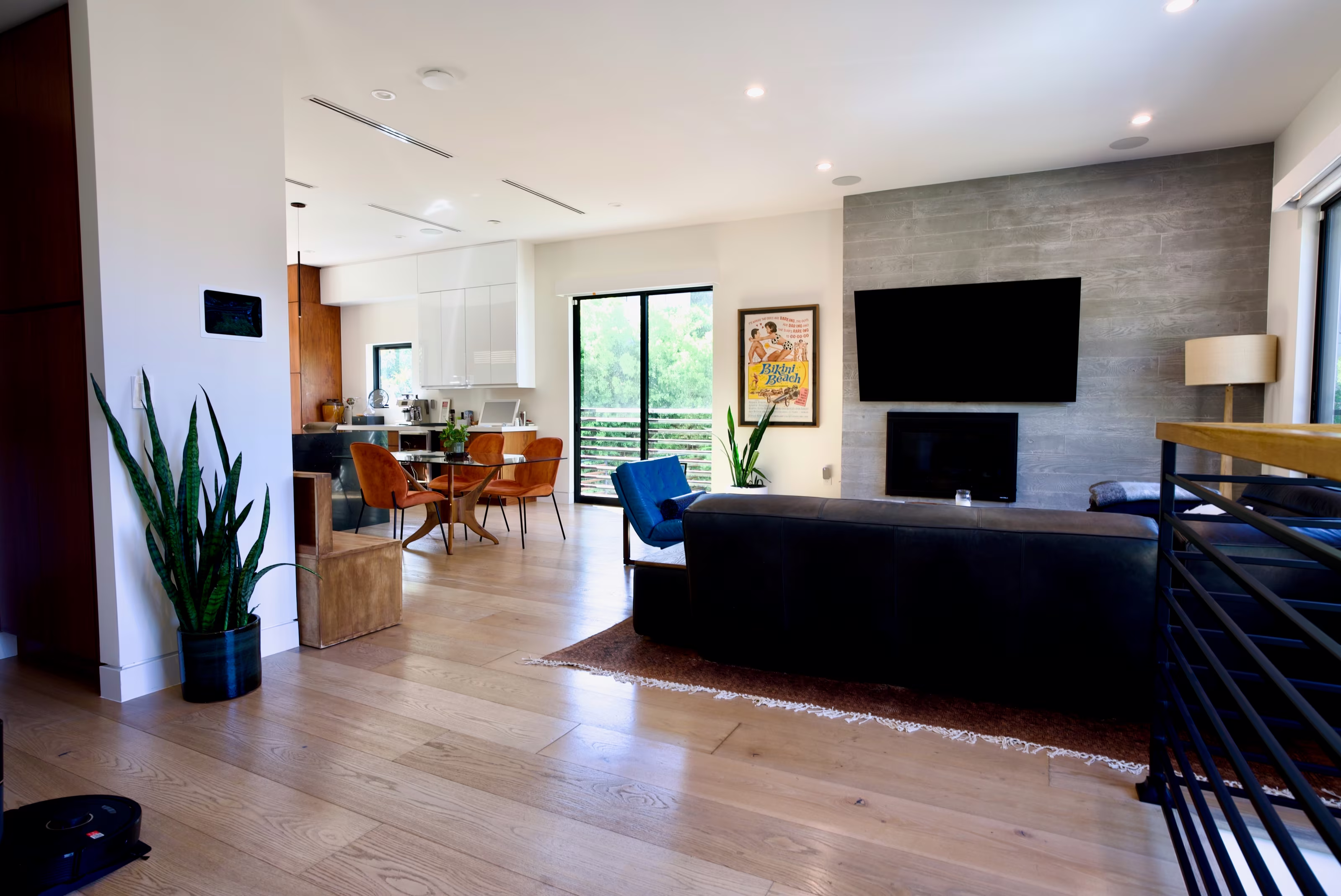 Open living area with black sofa facing a wall-mounted television and gray stone fireplace.