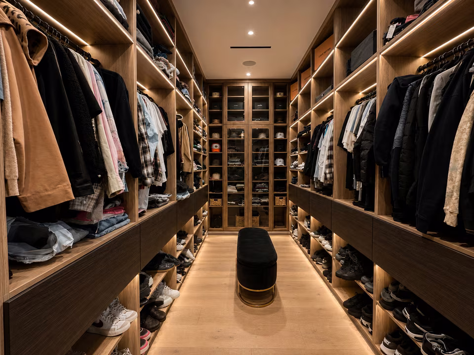 Large fitted walk-in closet with glass-front cabinetry, open shelving, a center island, and personal wardrobe storage.