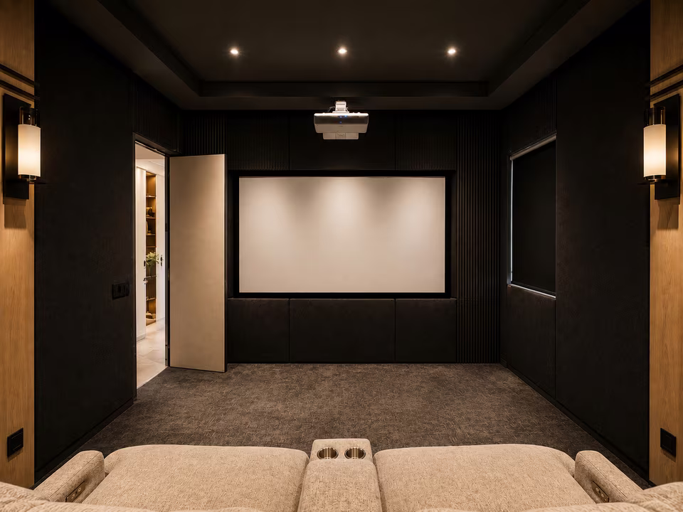 Wide home theater view with multiple rows of leather seating, a large screen, dark walls, and recessed lighting.