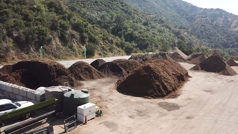 Layered view of large soil, mulch, and aggregate piles arranged across the outdoor industrial yard.